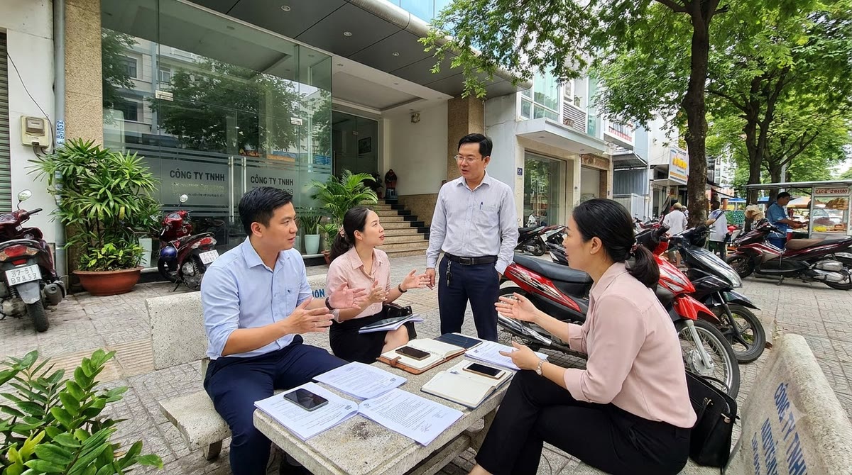 Nhóm marketing đứng ngoài tòa nhà kính ở TP.HCM với giấy in và điện thoại