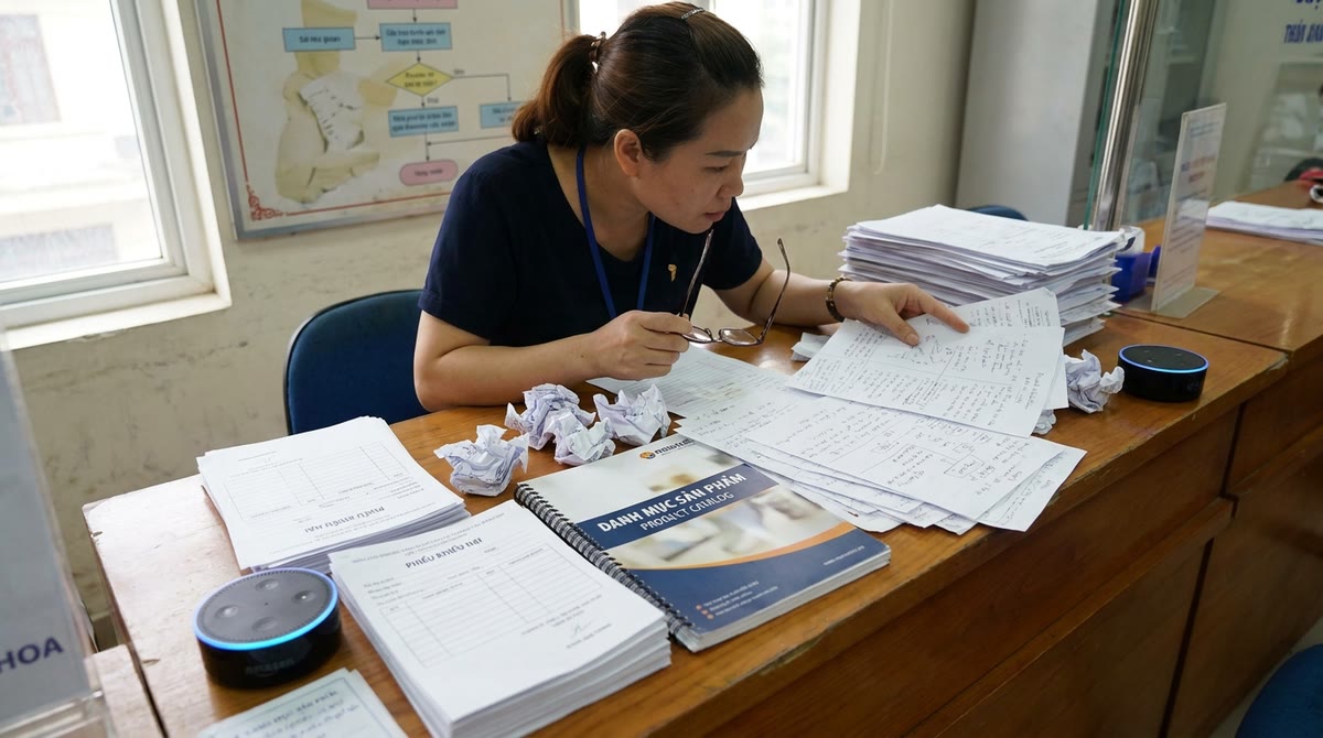 Quầy chăm sóc khách hàng Việt với form giấy, catalog và thiết bị trợ lý AI