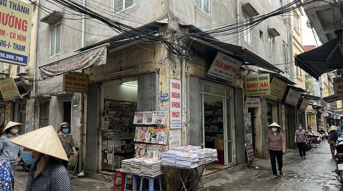 Hẻm phố Việt Nam với nhiều biển hiệu nhỏ, tờ rơi in và các mặt tiền cửa hàng nối dây chằng chịt
